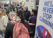 Students at career fair booth asking questions.